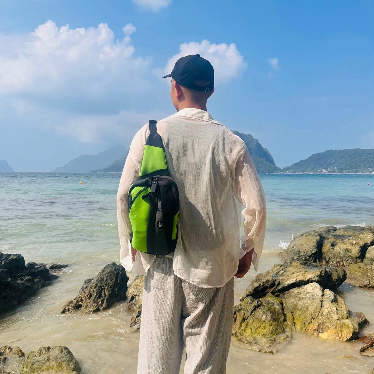 Sling crossbody bag with an adjustable strap, made from recycled materials worn on the beach. 