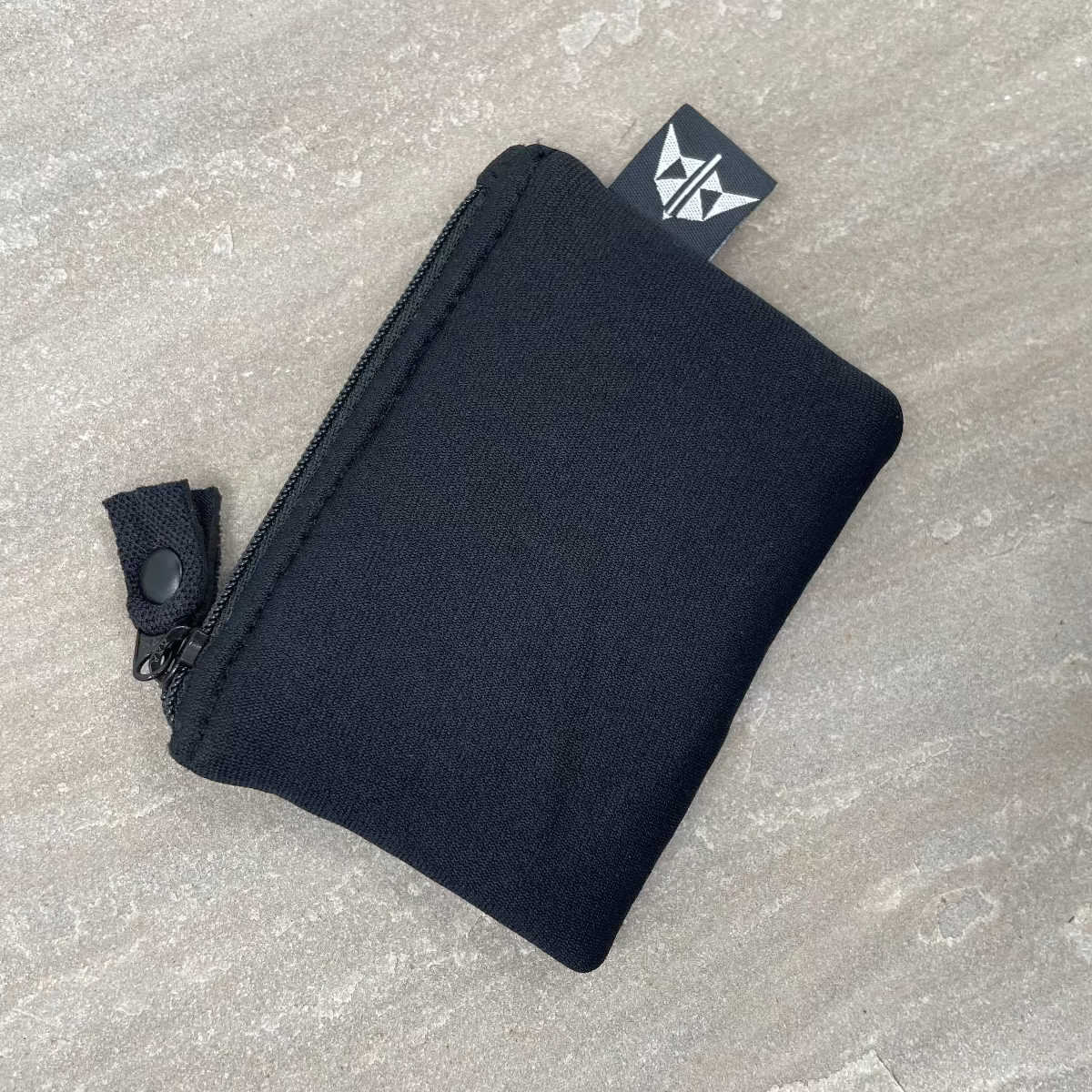 Black zippered pouch on a gray concrete surface