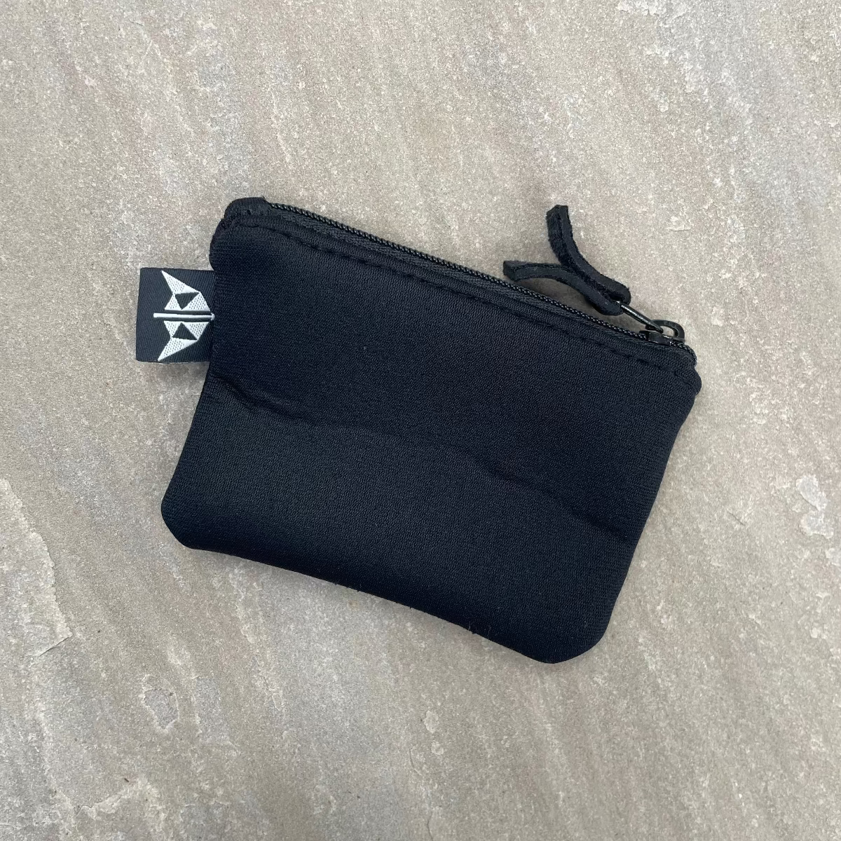 Black zippered pouch on a textured gray surface