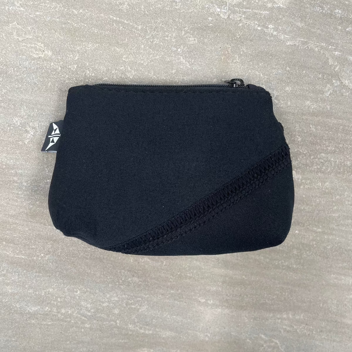 Black pouch with a brand tag on a gray textured background
