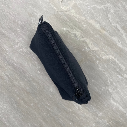 Black zippered pouch on a textured gray surface