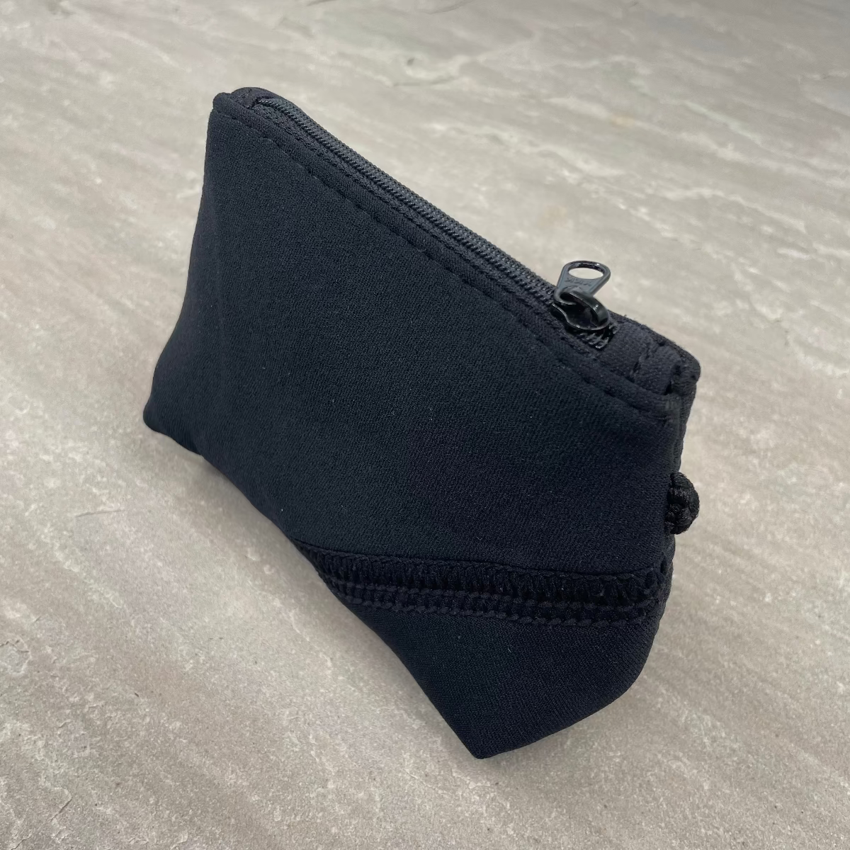 Black zippered pouch on a gray surface