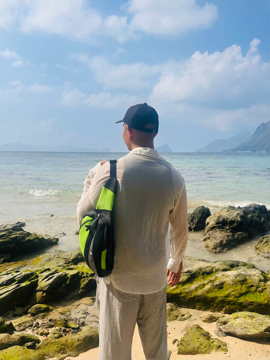 Sling crossbody bag with an adjustable strap, made from recycled materials worn on the beach. 